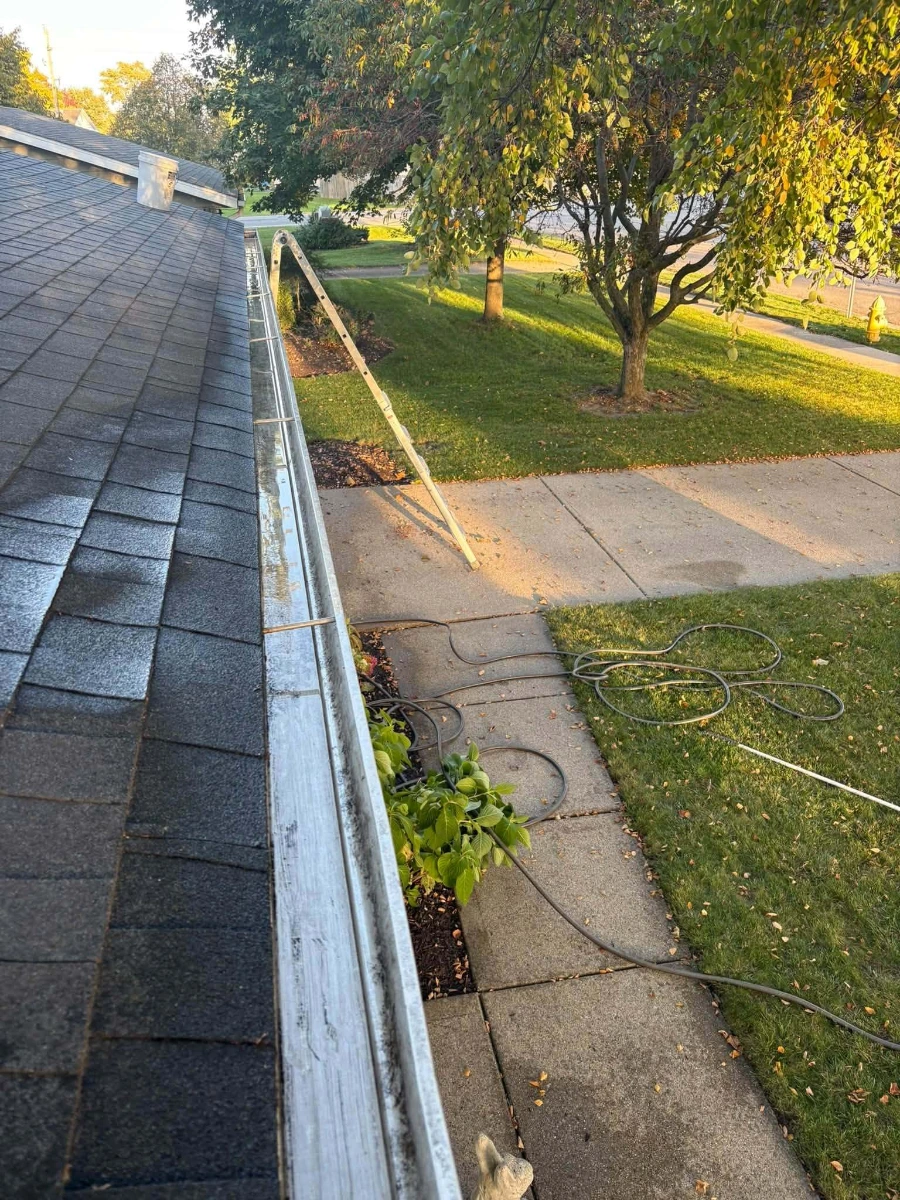 Clear aluminum gutter channel along a roofline after professional cleaning