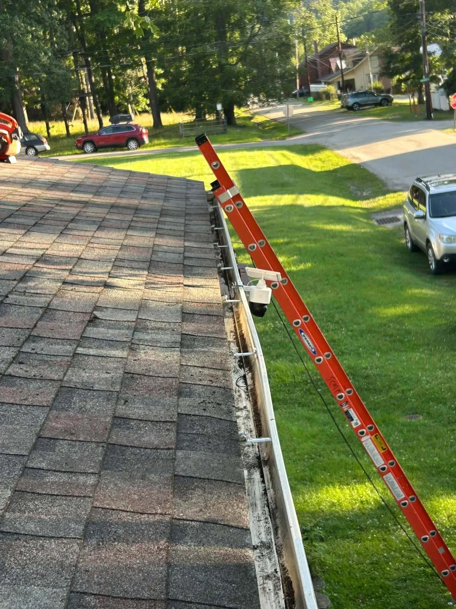 Orange extension ladder leaning against a roof edge during a gutter cleaning visit in Greenville, SC